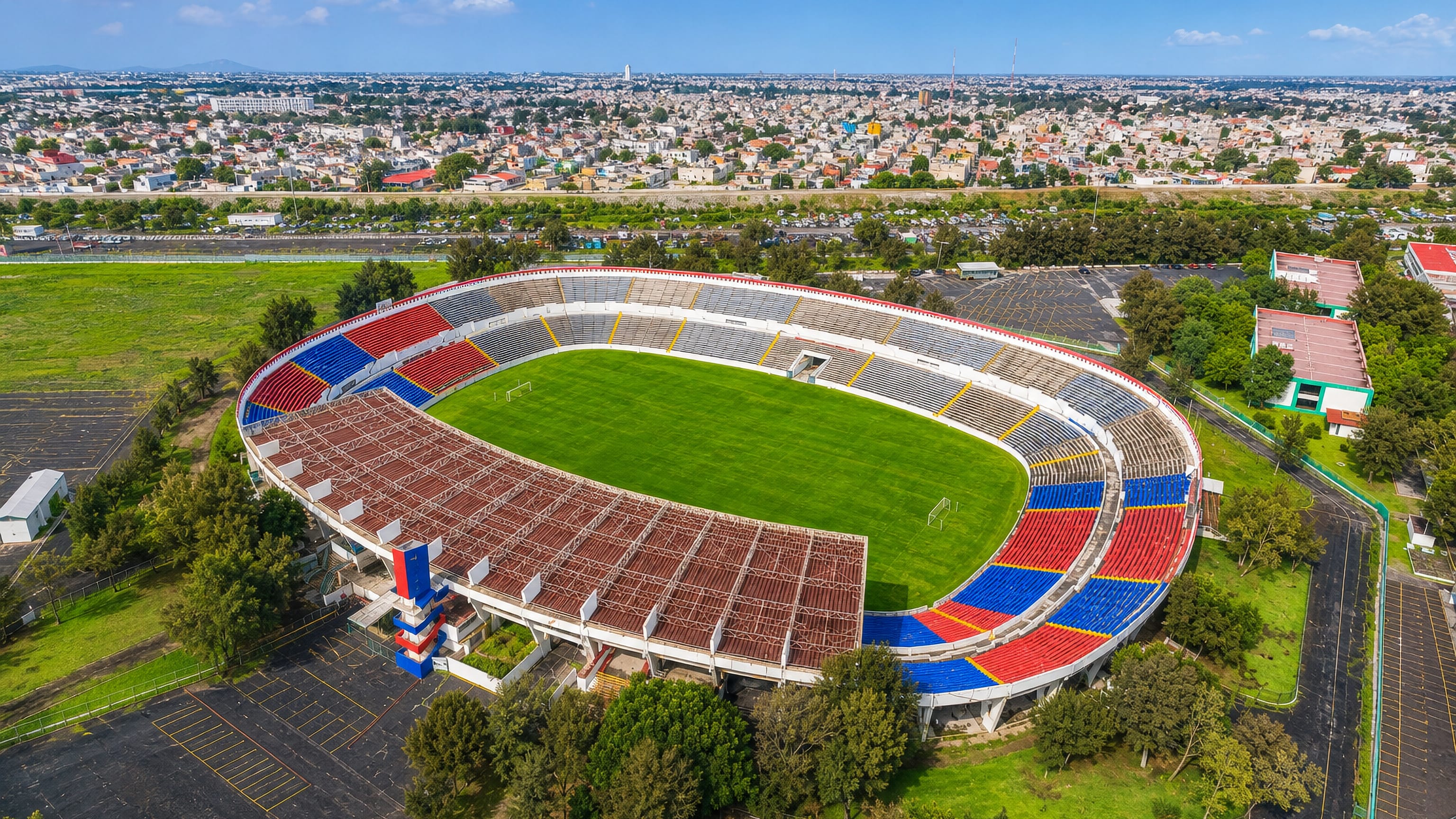 The open football stadium of Ciudad Nezahualcoyotl, Mexico, its red and blue stands ringed by the city's sprawl.