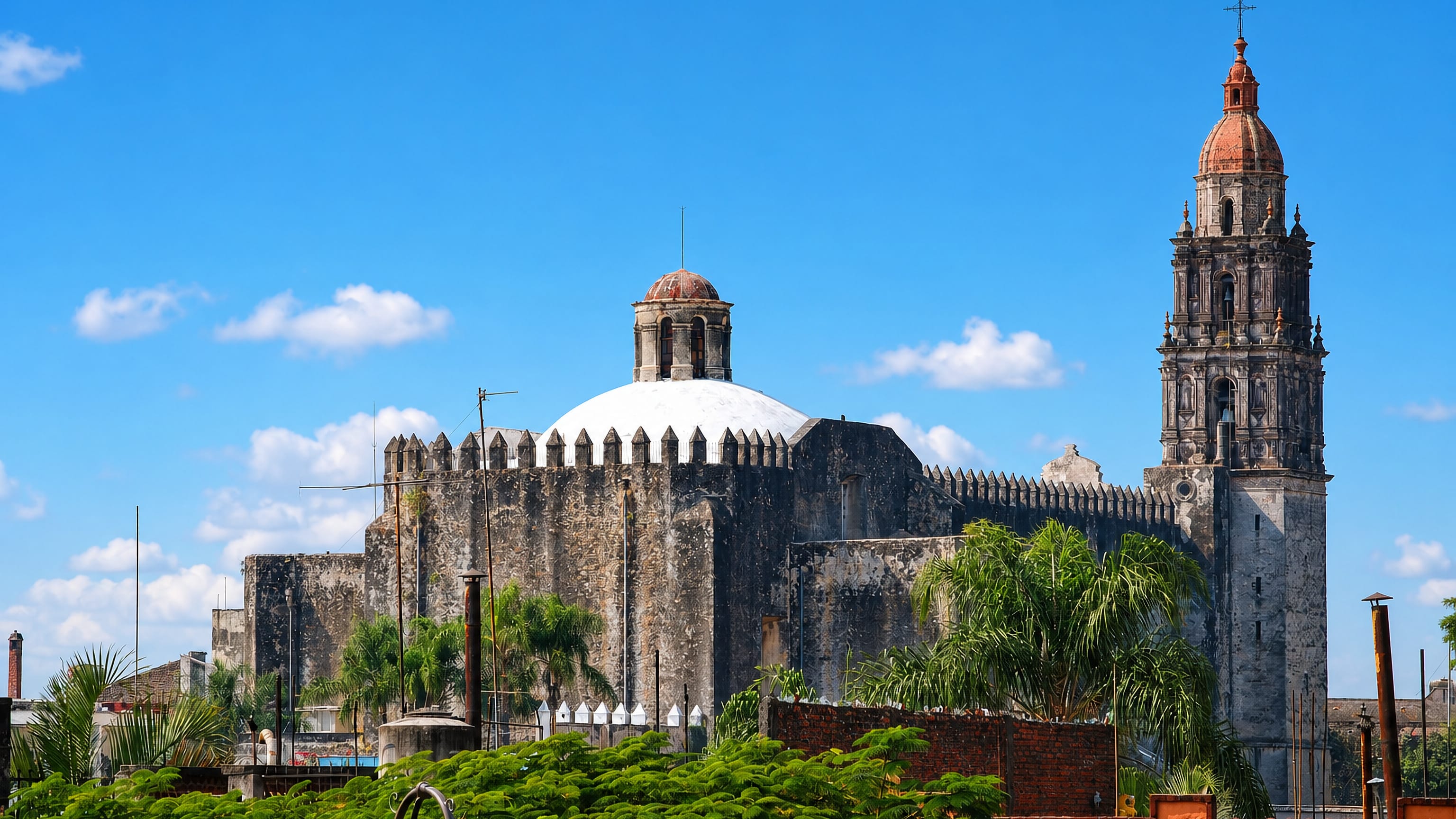 Cuernavaca Cathedral's fortress walls, white dome and baroque bell tower above palms in Cuernavaca, Mexico