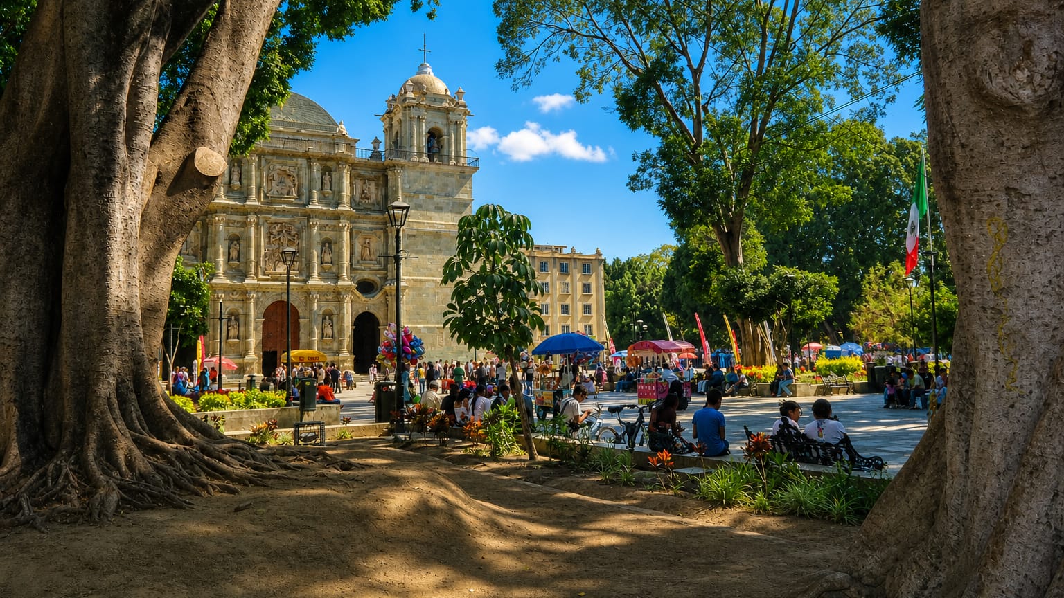 Oaxaca's Metropolitan Cathedral seen across the tree-shaded Alameda plaza with market crowds, Mexico