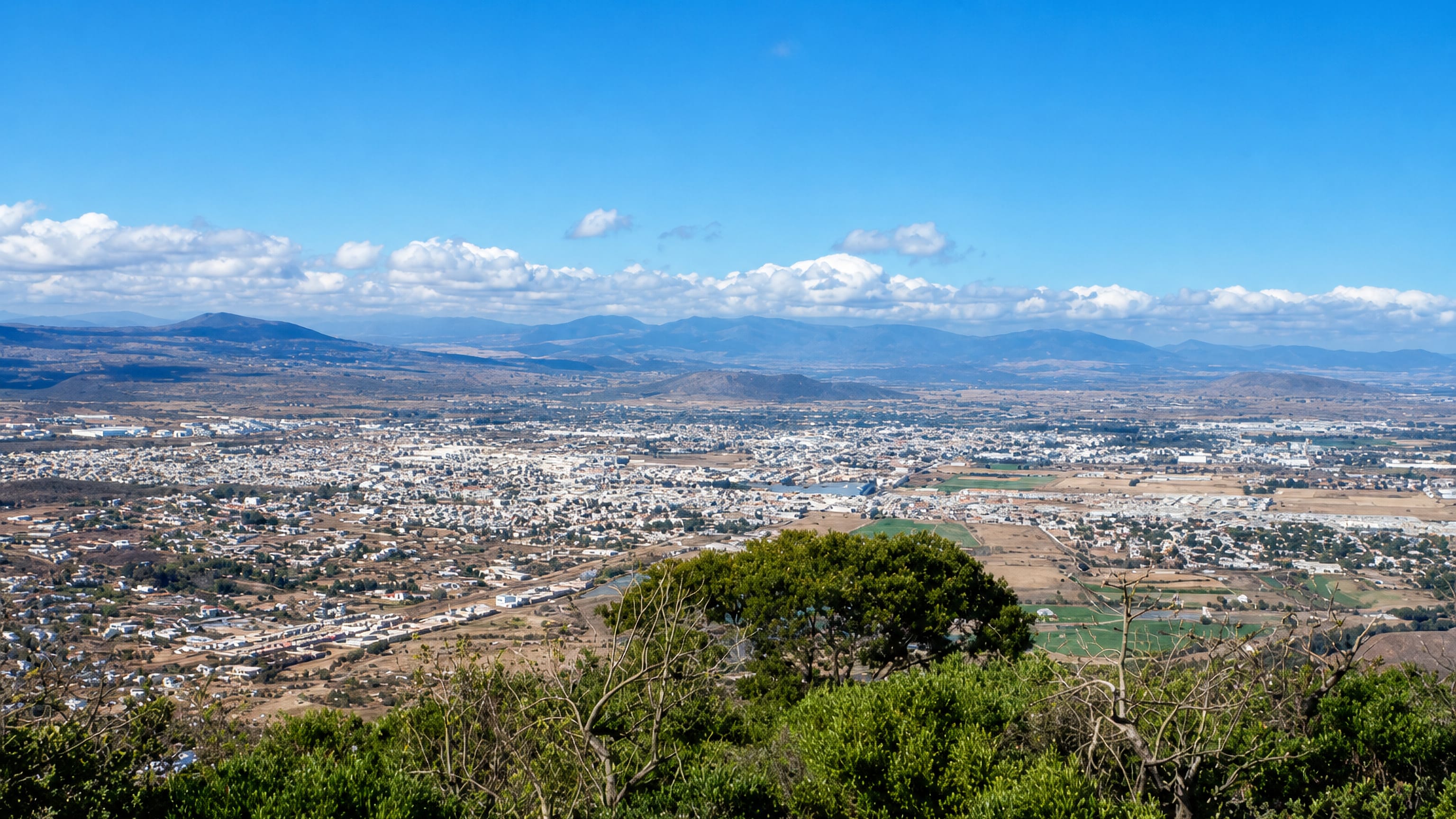 Panorama of San Juan del Río, Mexico, spread across its valley with mountains on the horizon.