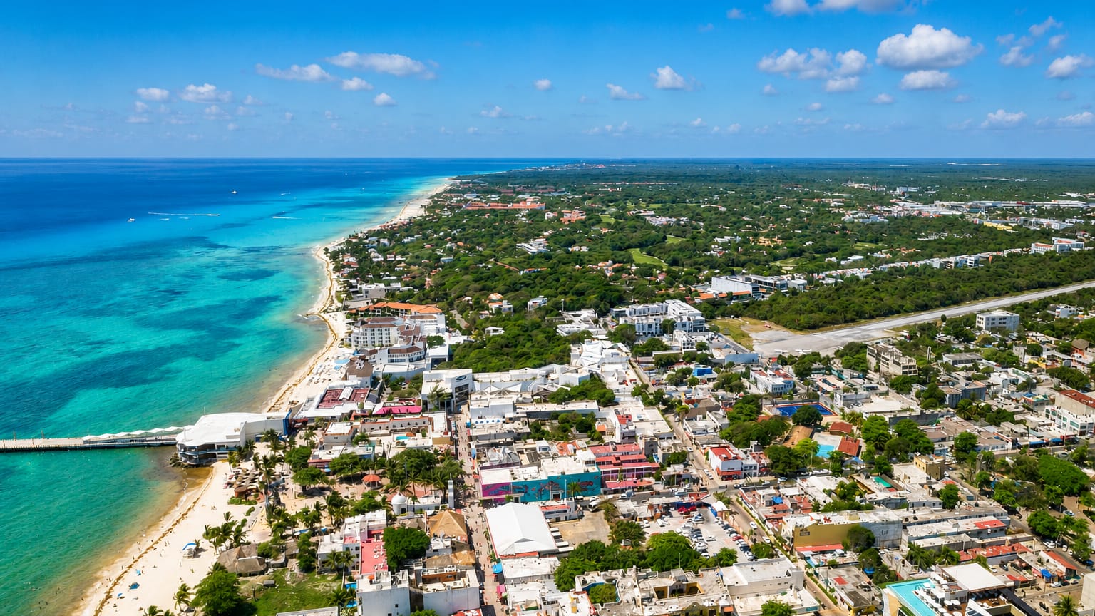Aerial view of Playa del Carmen's turquoise Caribbean shoreline, white-sand beach, pier and low-rise town.