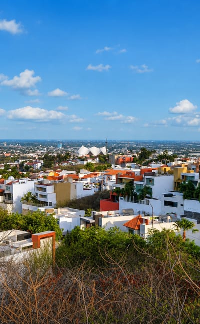 Hillside view over Culiacán's white and red-roofed houses spreading across the plain under a clear sky.