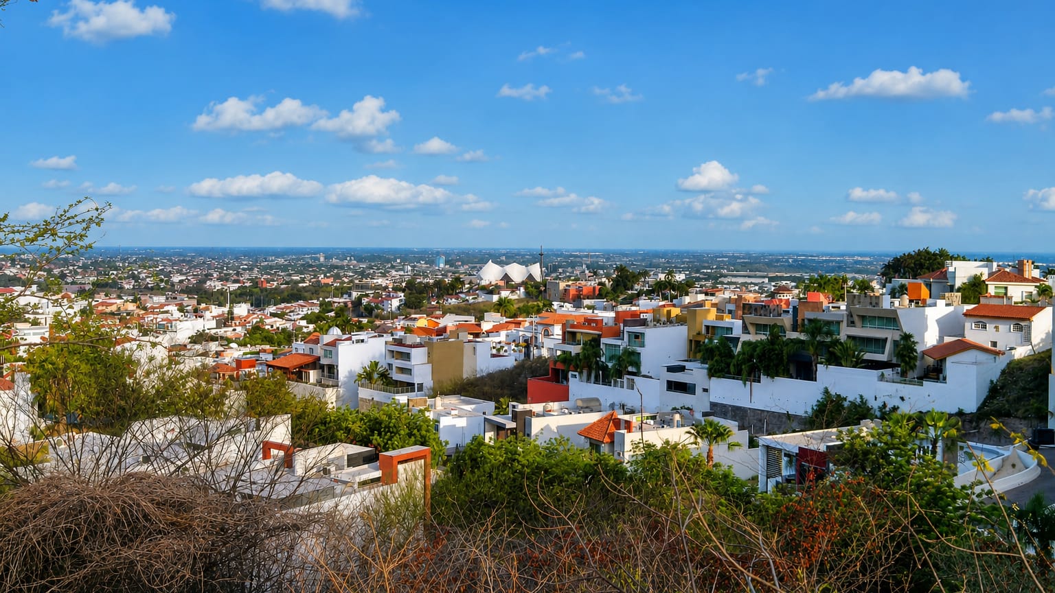 Hillside view over Culiacán's white and red-roofed houses spreading across the plain under a clear sky.