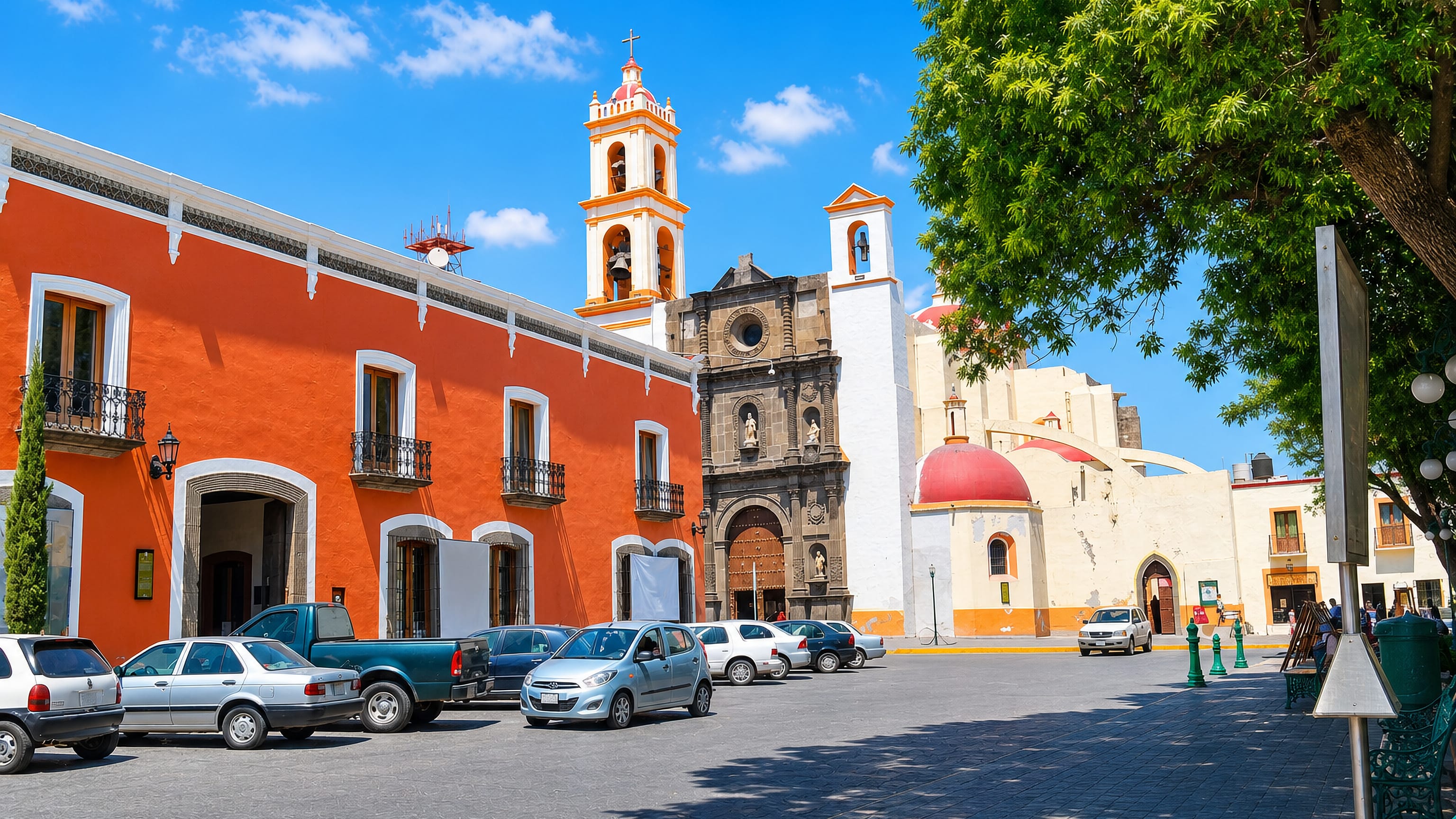 Colonial plaza with an orange arcaded palace and red-domed baroque church in Huamantla, Tlaxcala, Mexico.