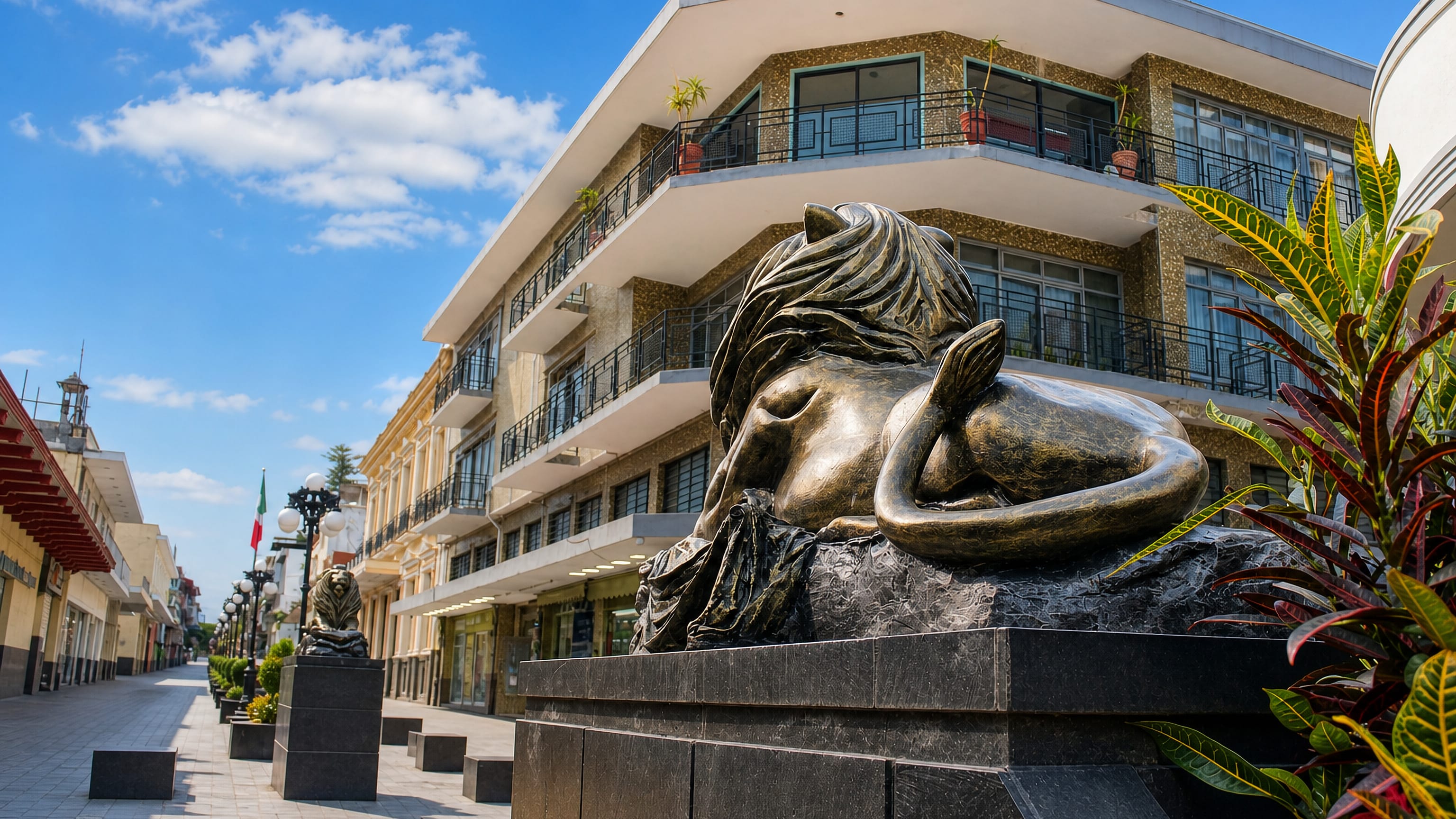 Bronze sculpture on a pedestrian boulevard lined with mid-century buildings in Orizaba, Mexico.