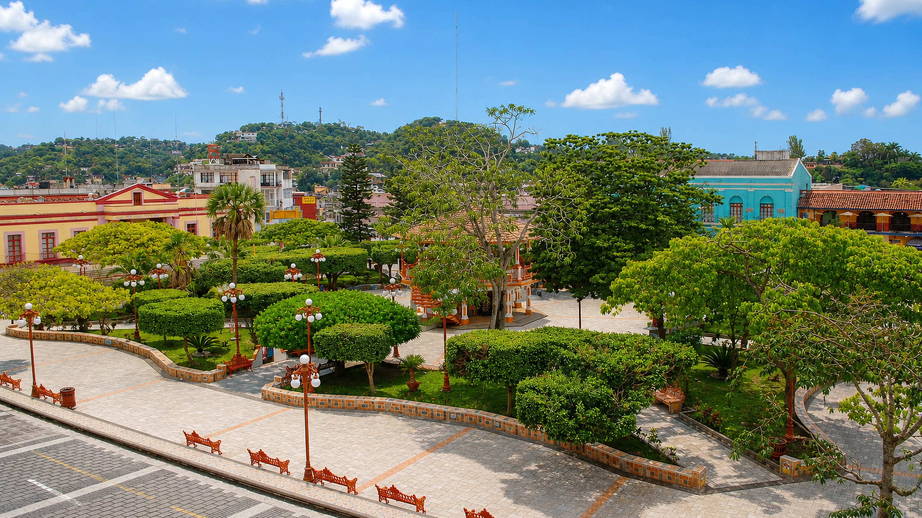Leafy central plaza with bandstand, colourful facades and green hills behind in Papantla de Olarte, Veracruz.
