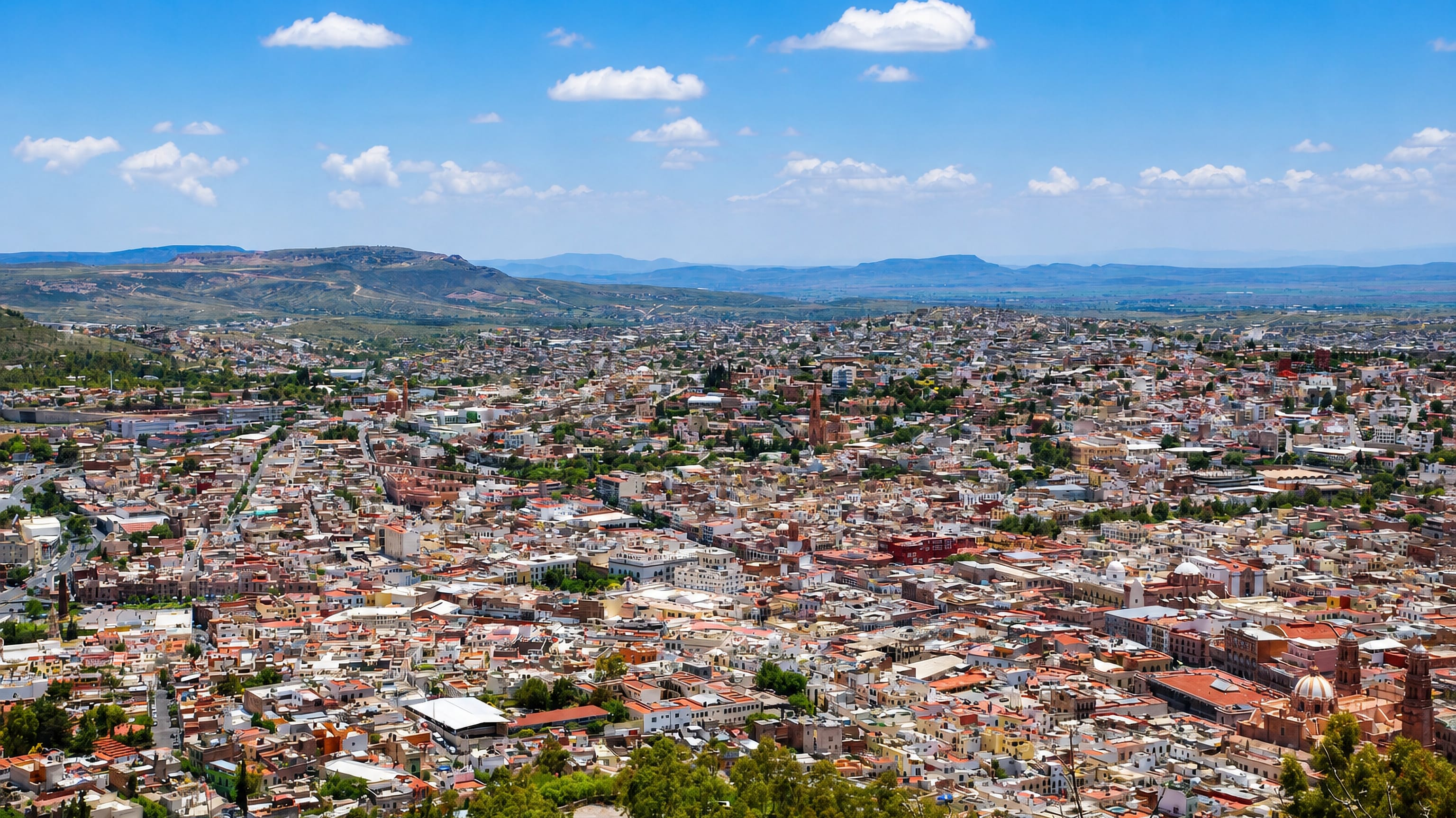 Hillside view over the colonial centre of Zacatecas, Mexico, with its pink stone cathedral dome and surrounding sierra.