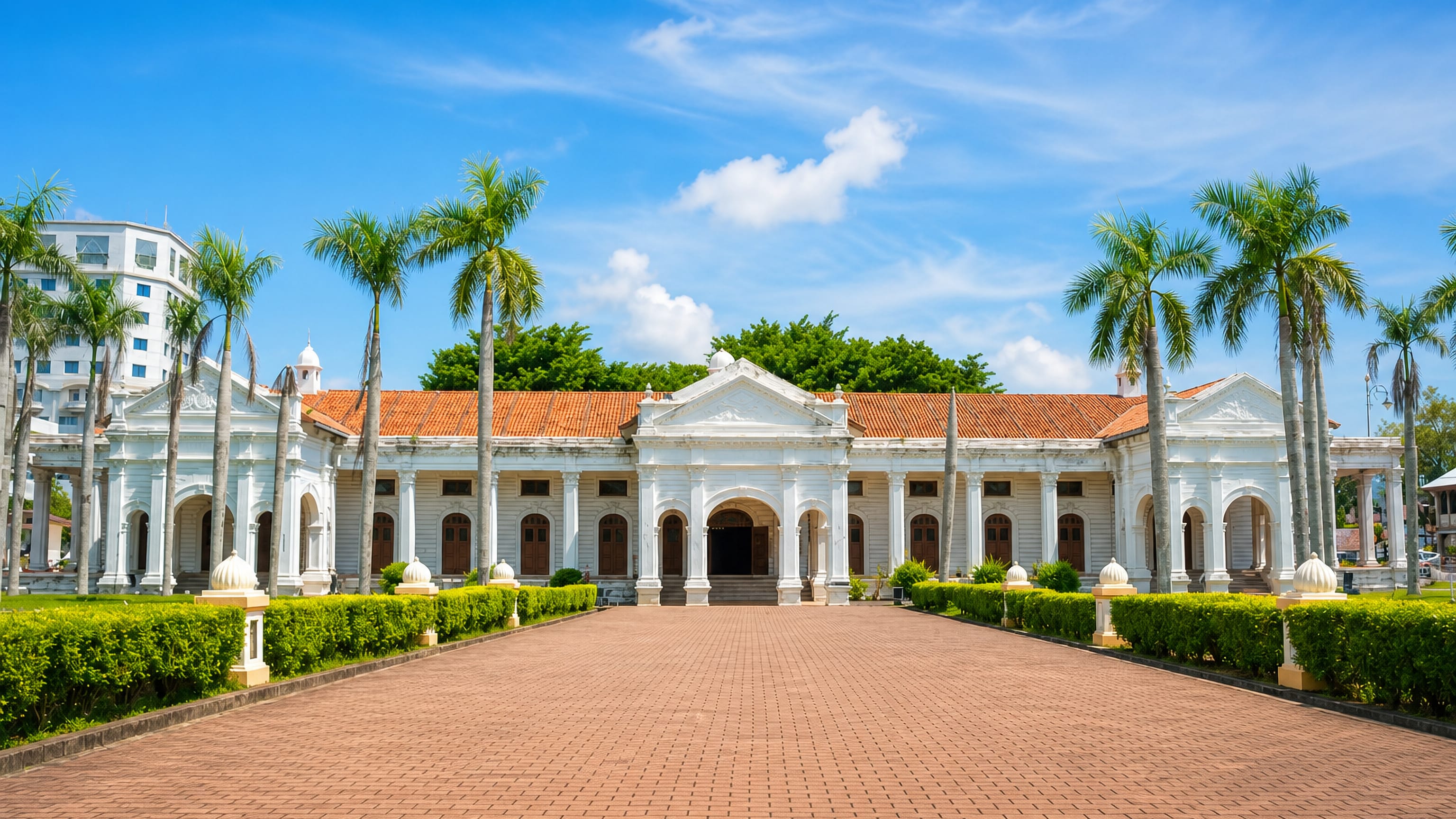 White colonnaded colonial civic building with a red tile roof and palms in Alor Setar, Malaysia.