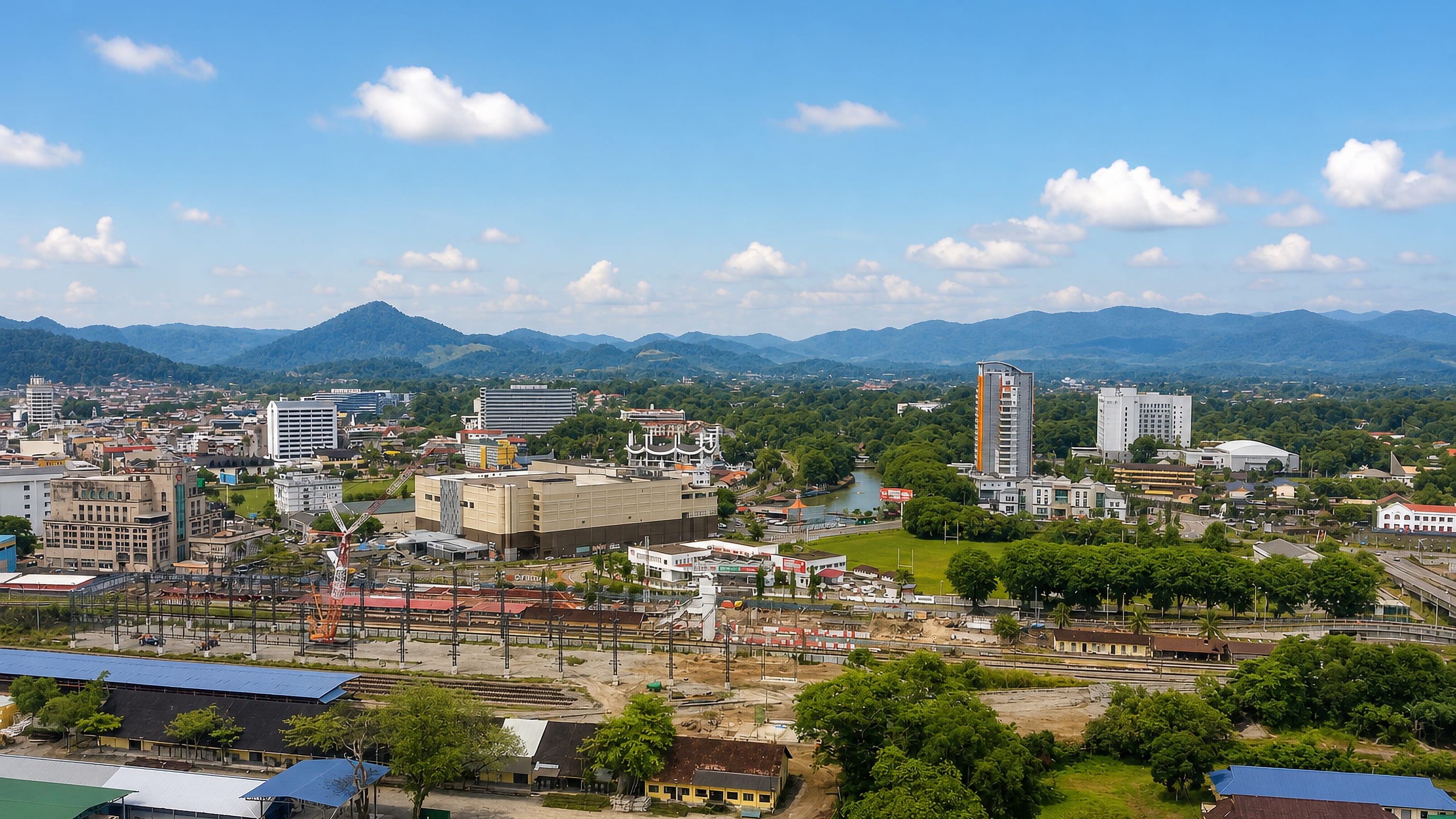 Aerial view of Seremban, Malaysia, with its railway yard, town-centre blocks and forested hills beyond.