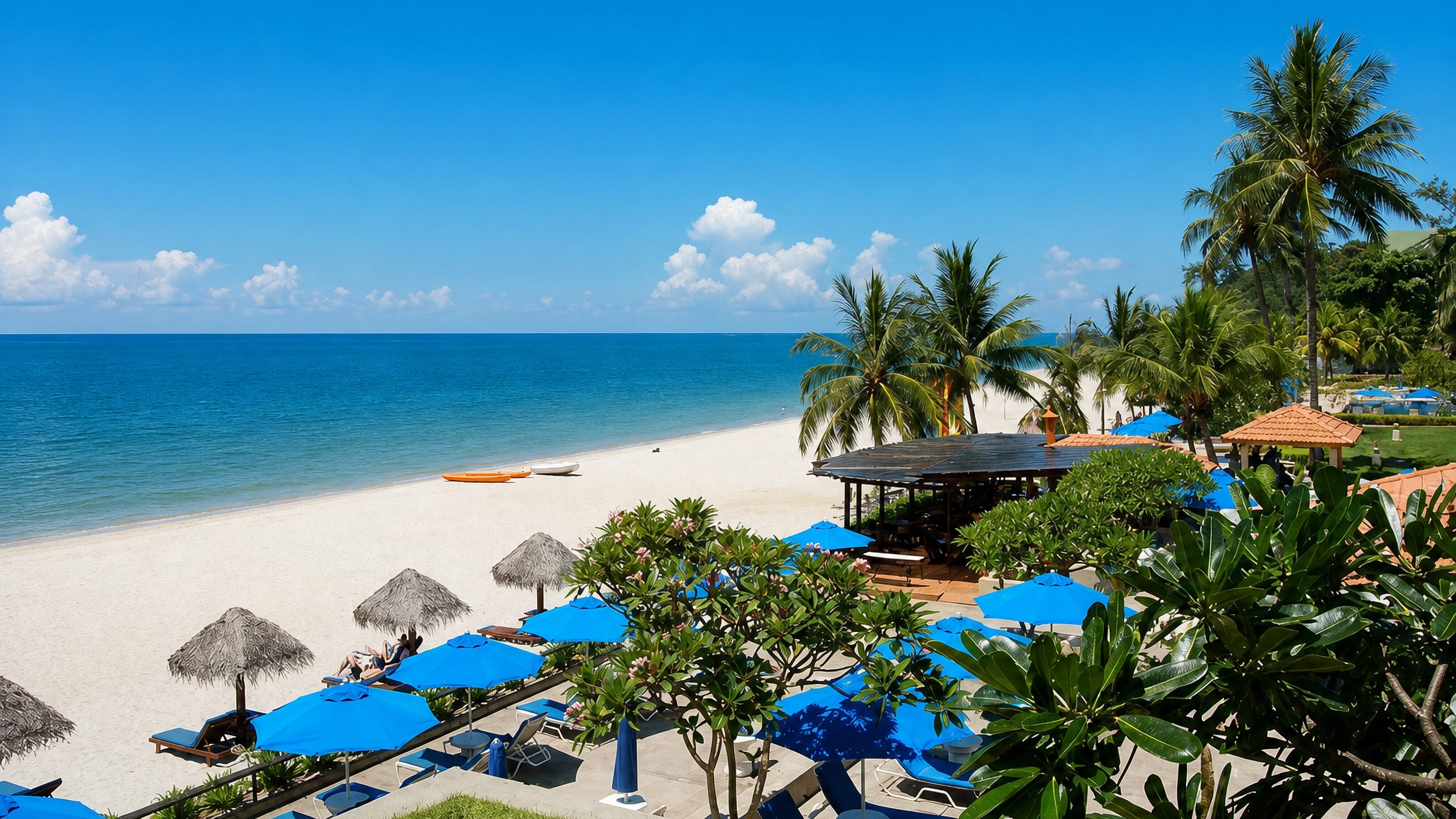 Palm-fringed white-sand beach with blue parasols on the South China Sea coast at Kuantan, Pahang.