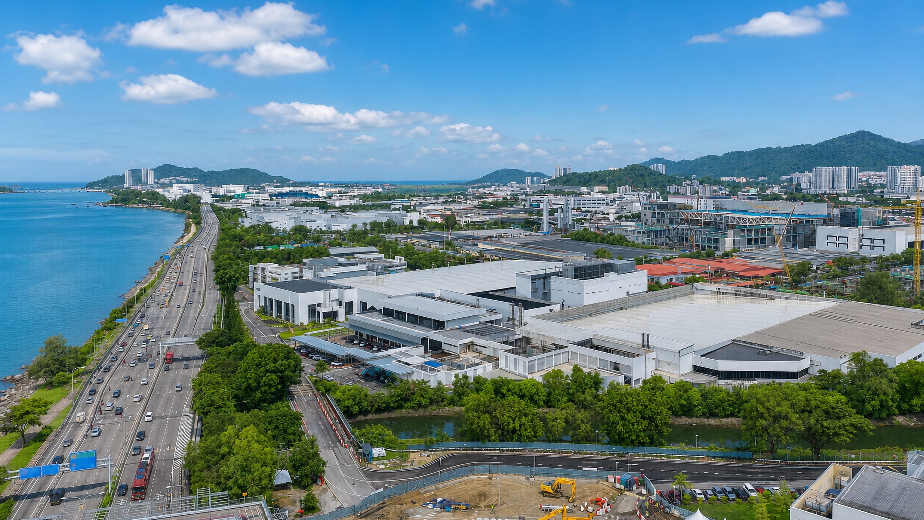 Coastal expressway and industrial estates of Bayan Lepas, Penang, with the sea on one side and green hills behind.