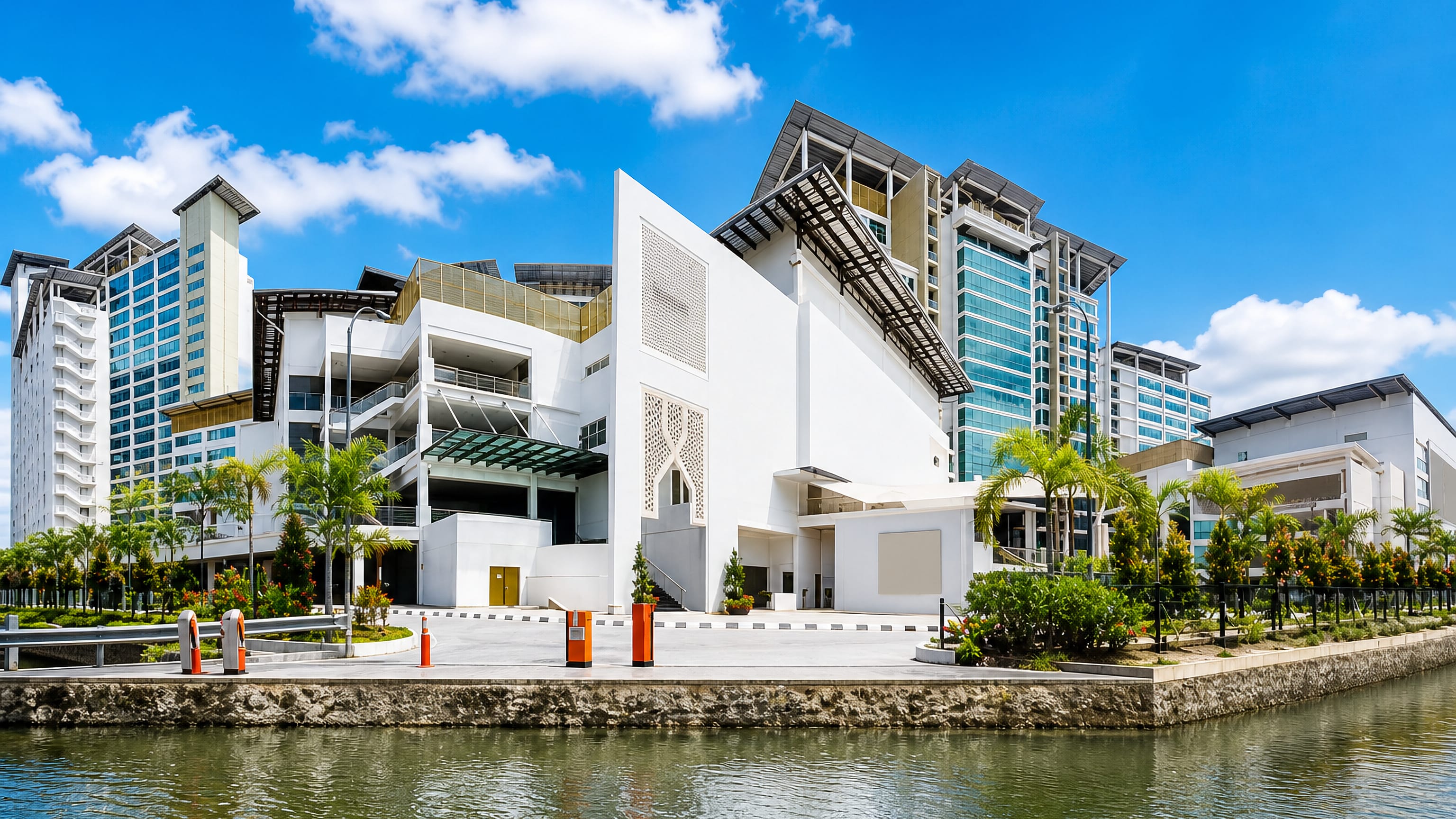 Modern white waterfront complex with Islamic latticework and glass towers beside a canal in Shah Alam, Malaysia