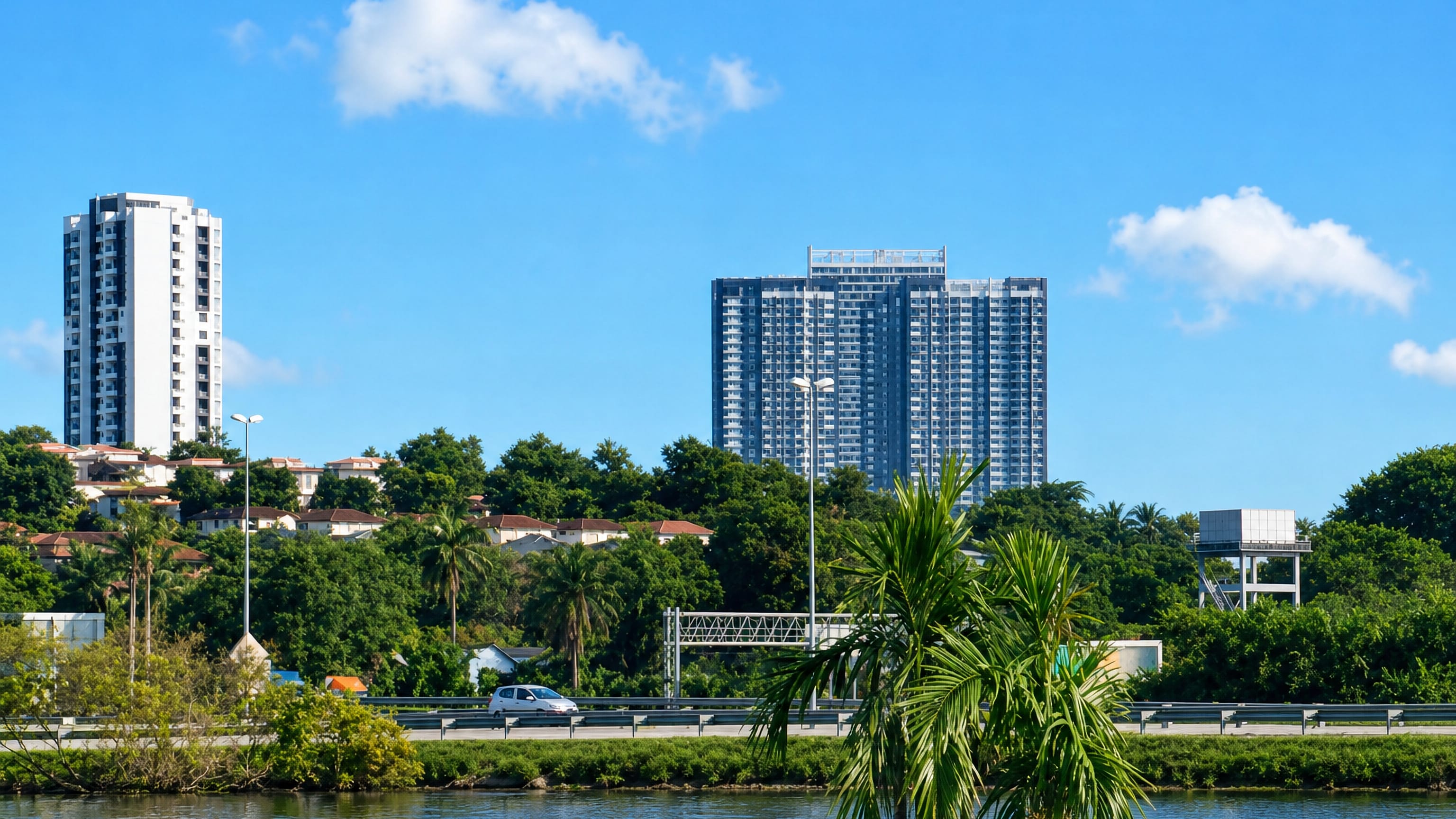 Condominium towers above tropical greenery and a highway beside water in Sungai Buloh, Selangor