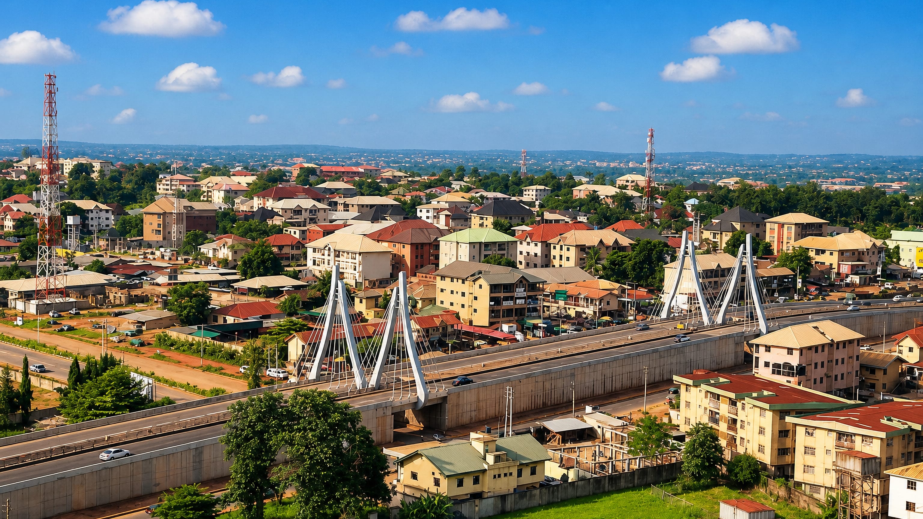 Awka's cable-stayed flyover crossing the expressway amid red-roofed houses and the green hills of Anambra State.