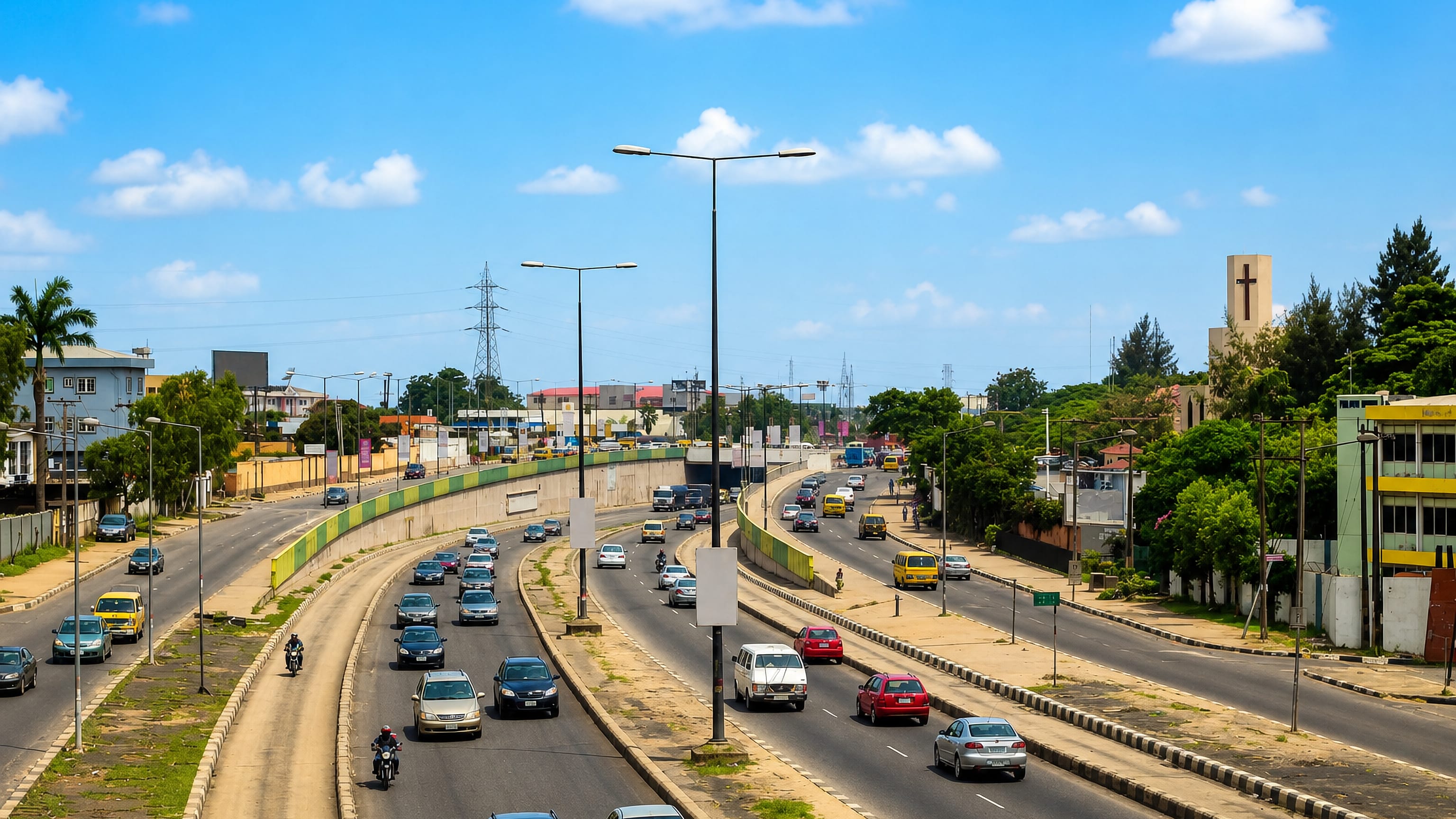 Yellow danfo buses and traffic on the broad expressway through Ikeja, Lagos, past a concrete church tower.