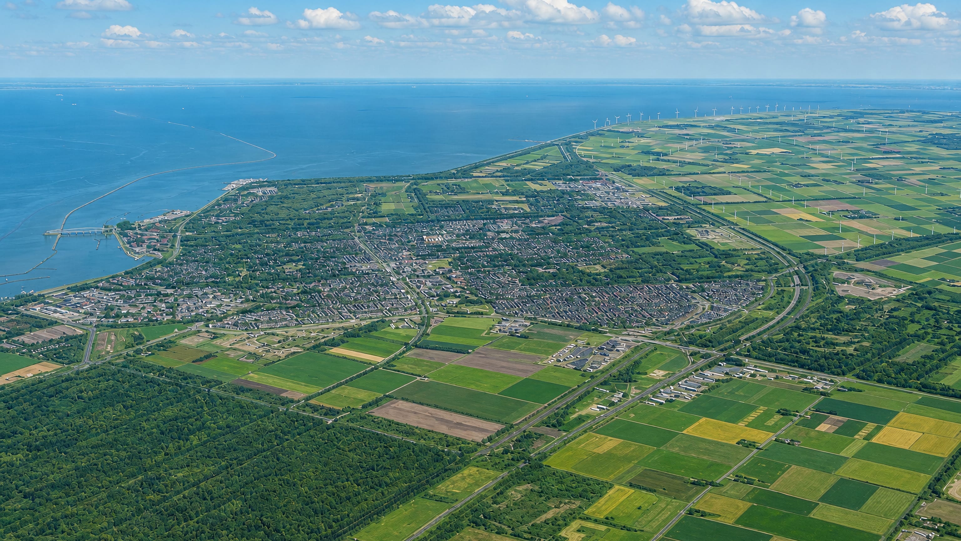 Aerial view of Lelystad on the Flevoland polder, with IJsselmeer shoreline, dyke and wind turbines.