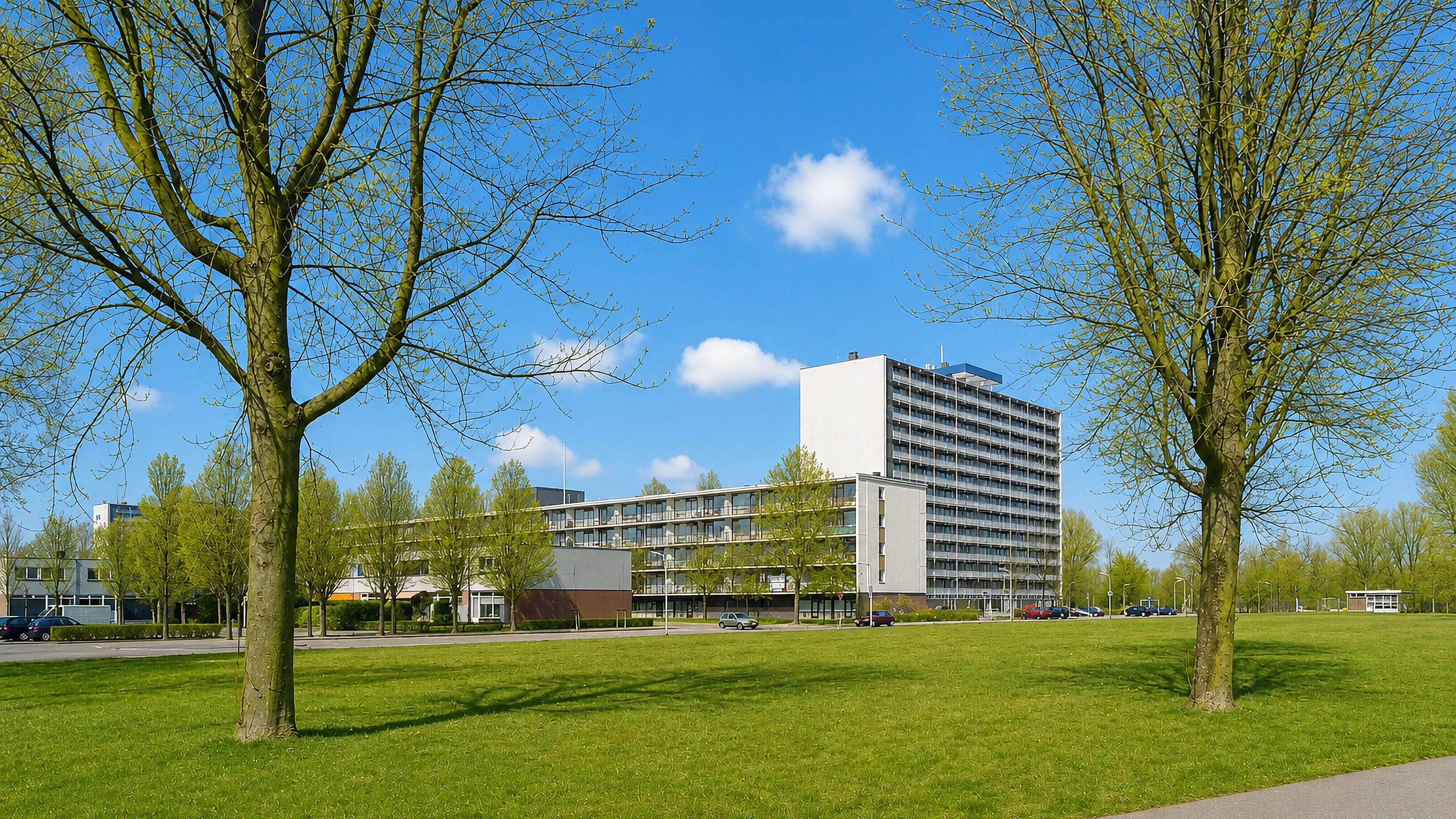 Green parkland and modernist gallery flats with a white tower block in Bilgaard, Leeuwarden.