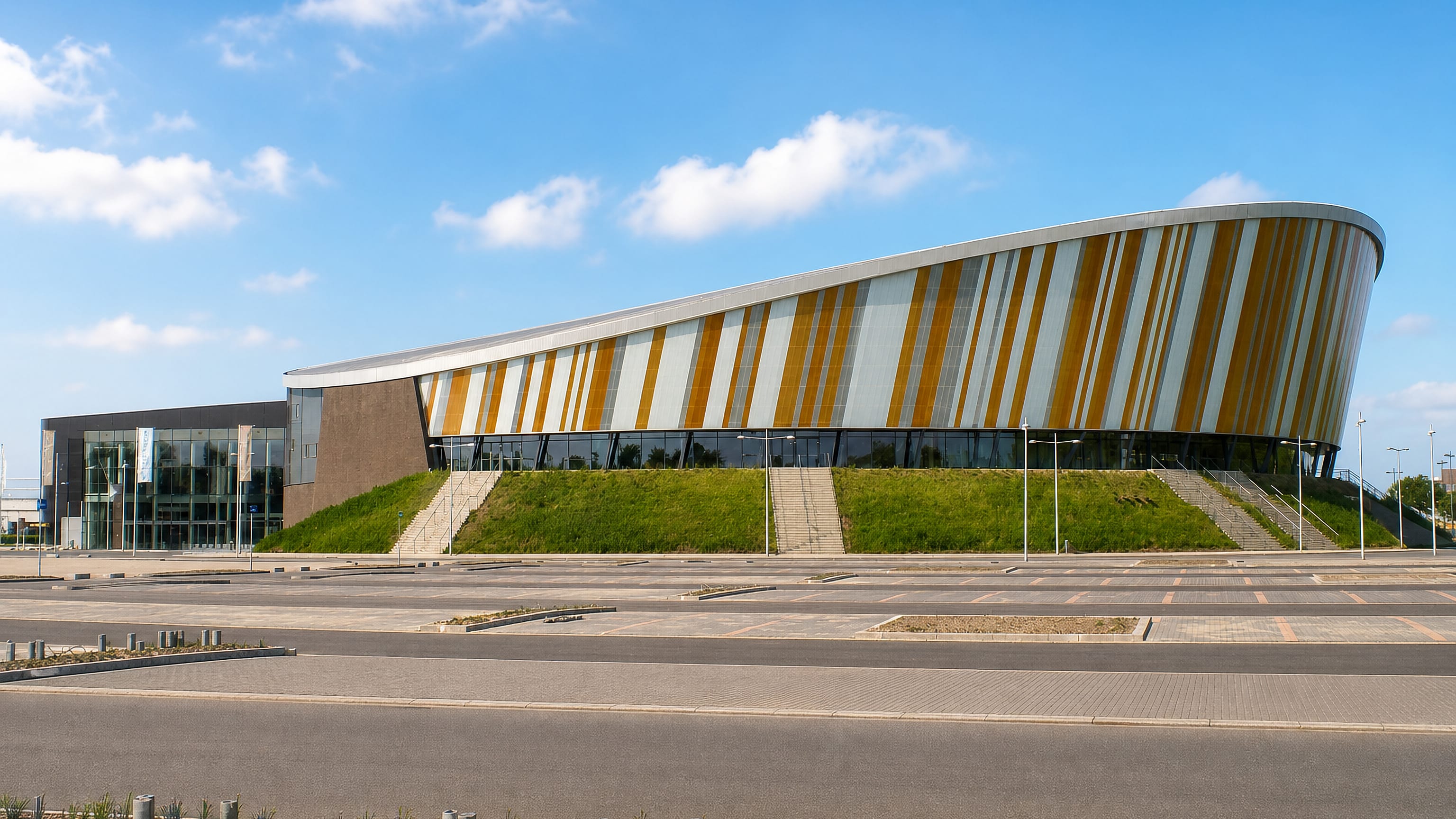 Curved striped facade of a modern arena beside an empty car park in Apeldoorn, Netherlands