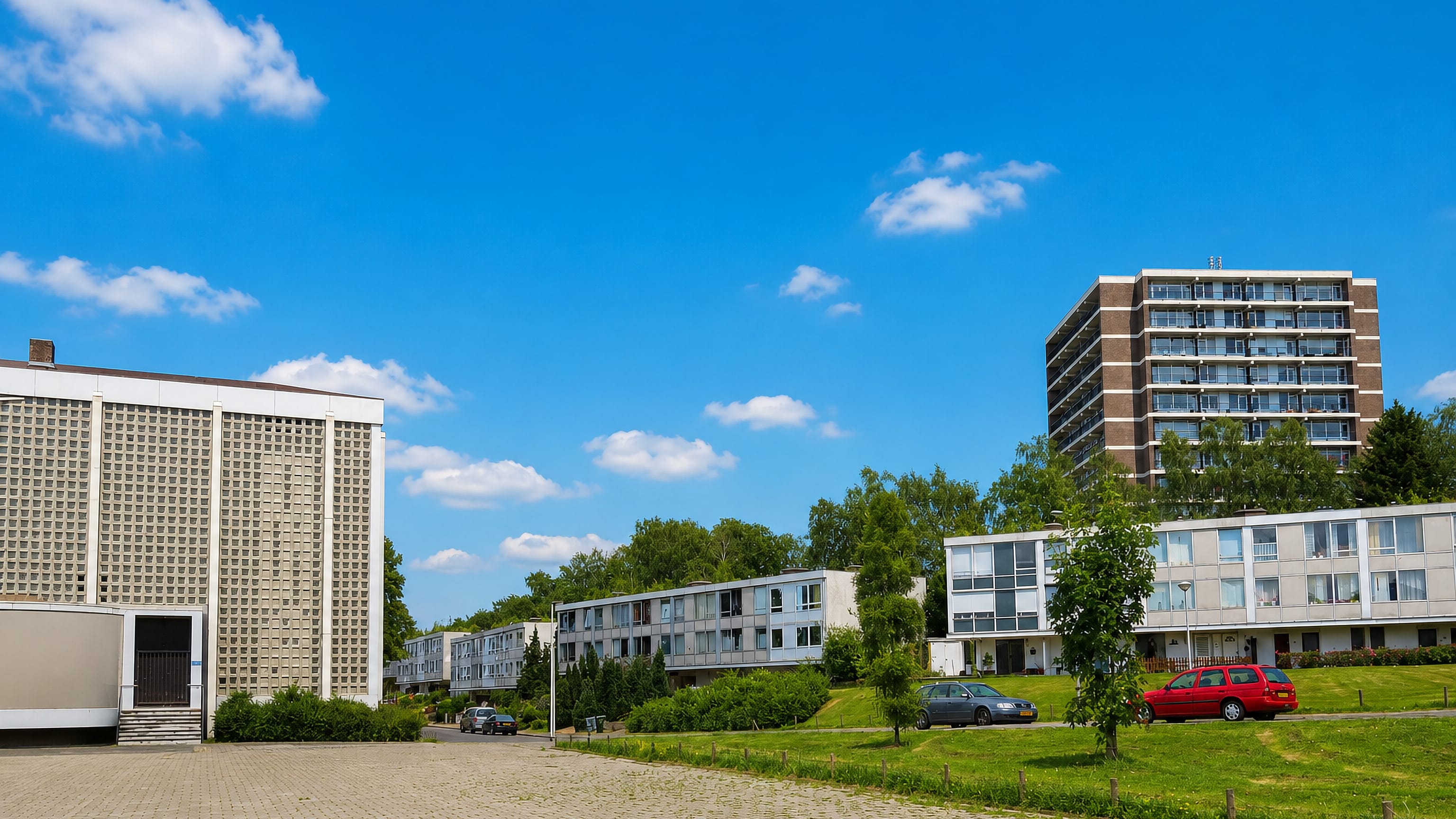 Post-war low-rise blocks and a tower block around open lawns and brick paving in Vrieheide, Heerlen.