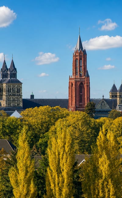Maastricht skyline with the Sint-Jan red church tower and Sint-Servaas basilica rising above autumn trees