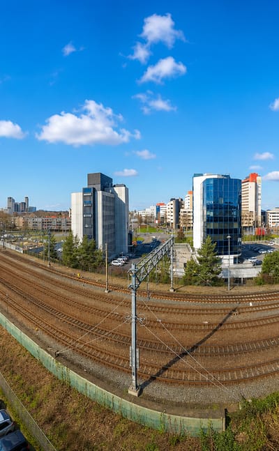 Eindhoven skyline of office towers beyond rail tracks, with the Philips Stadion visible to the left