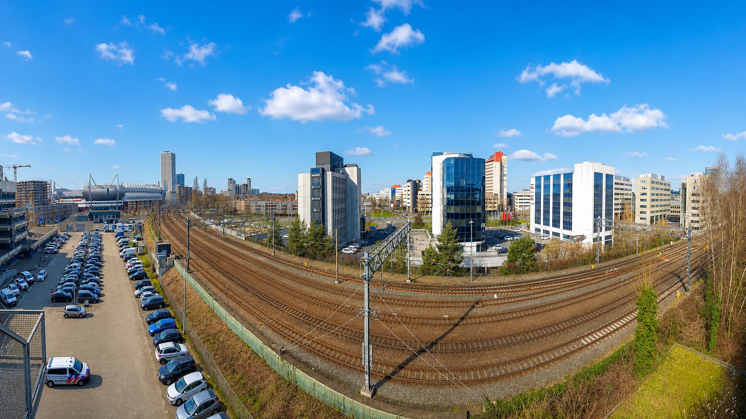 Eindhoven skyline of office towers beyond rail tracks, with the Philips Stadion visible to the left
