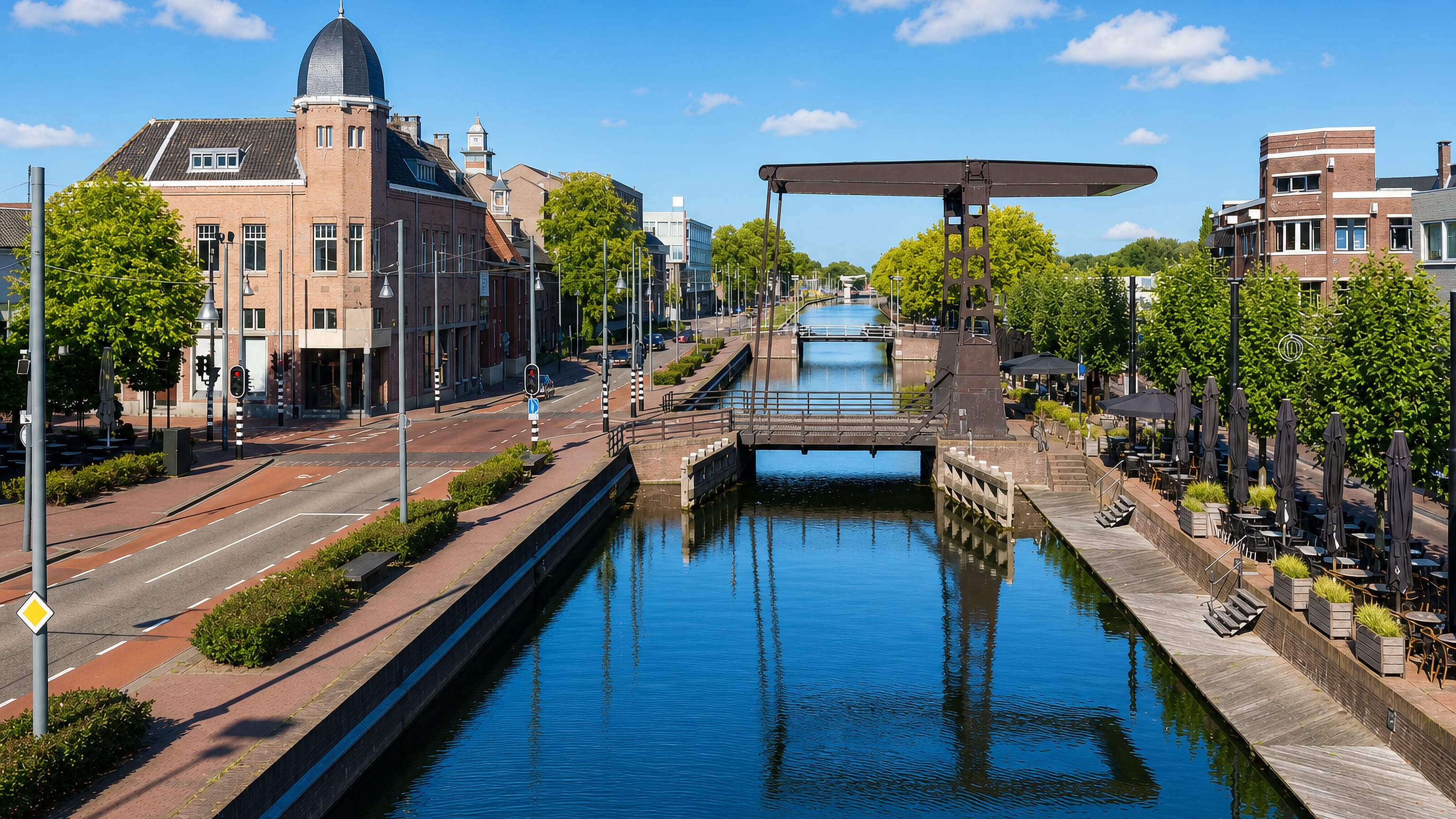 Canal running through central Helmond with a steel lift bridge, brick townhouses and waterside cafe terraces.