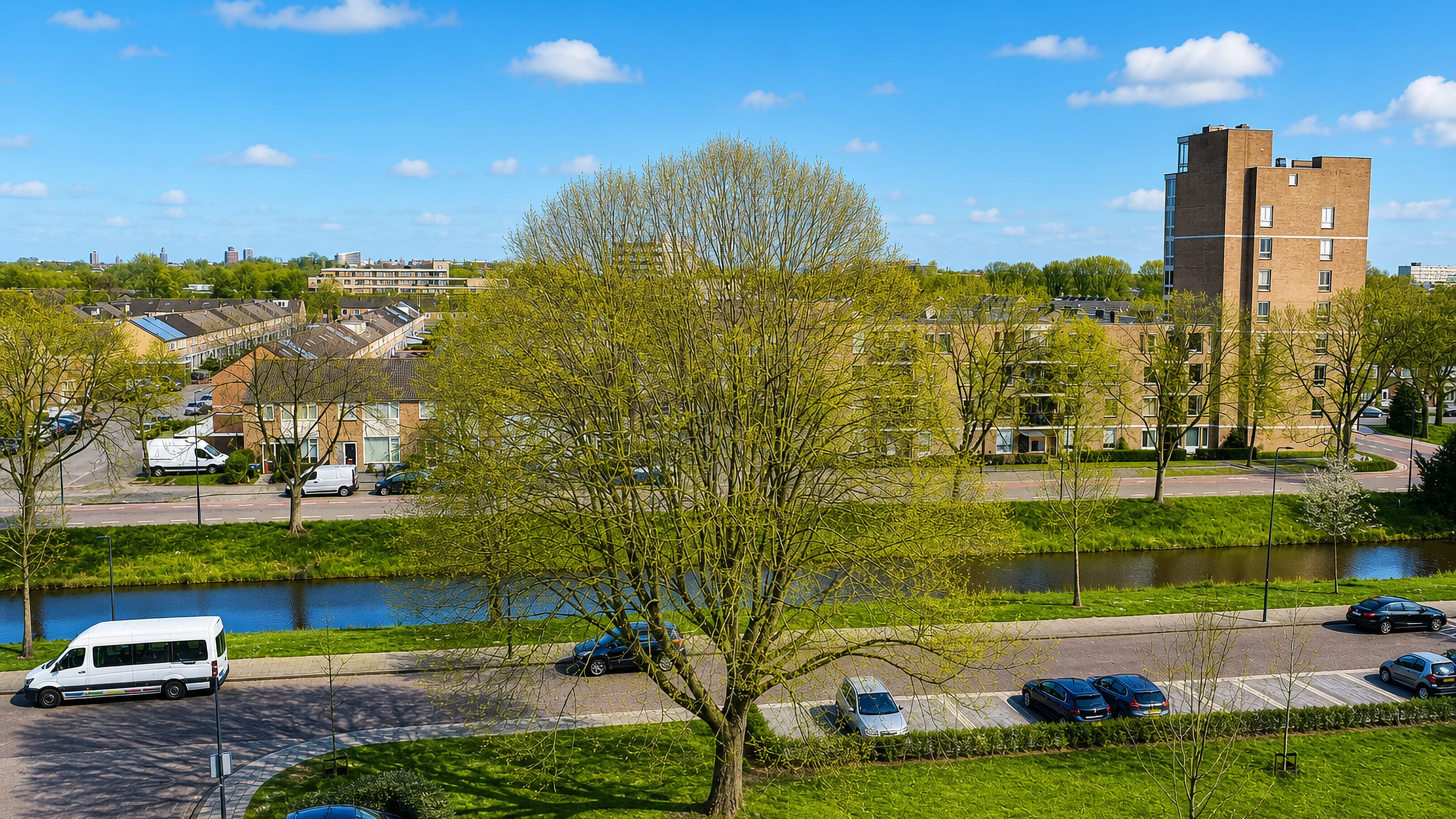 Brick terraces and a tall apartment block beside a canal in De Kruiskamp, 's-Hertogenbosch.