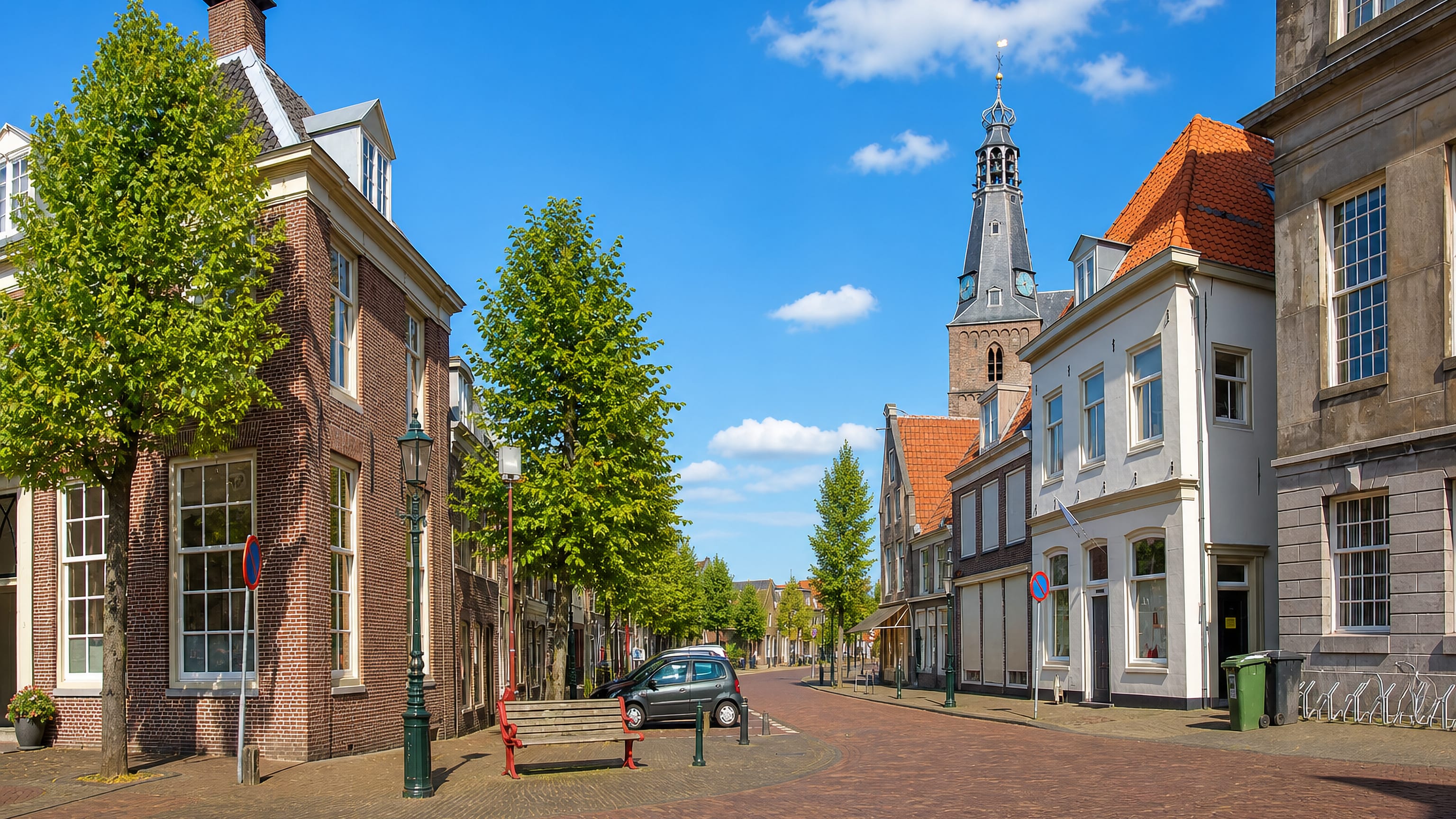 Brick townhouses and a slender church tower above a cobbled street in Weesp, North Holland.