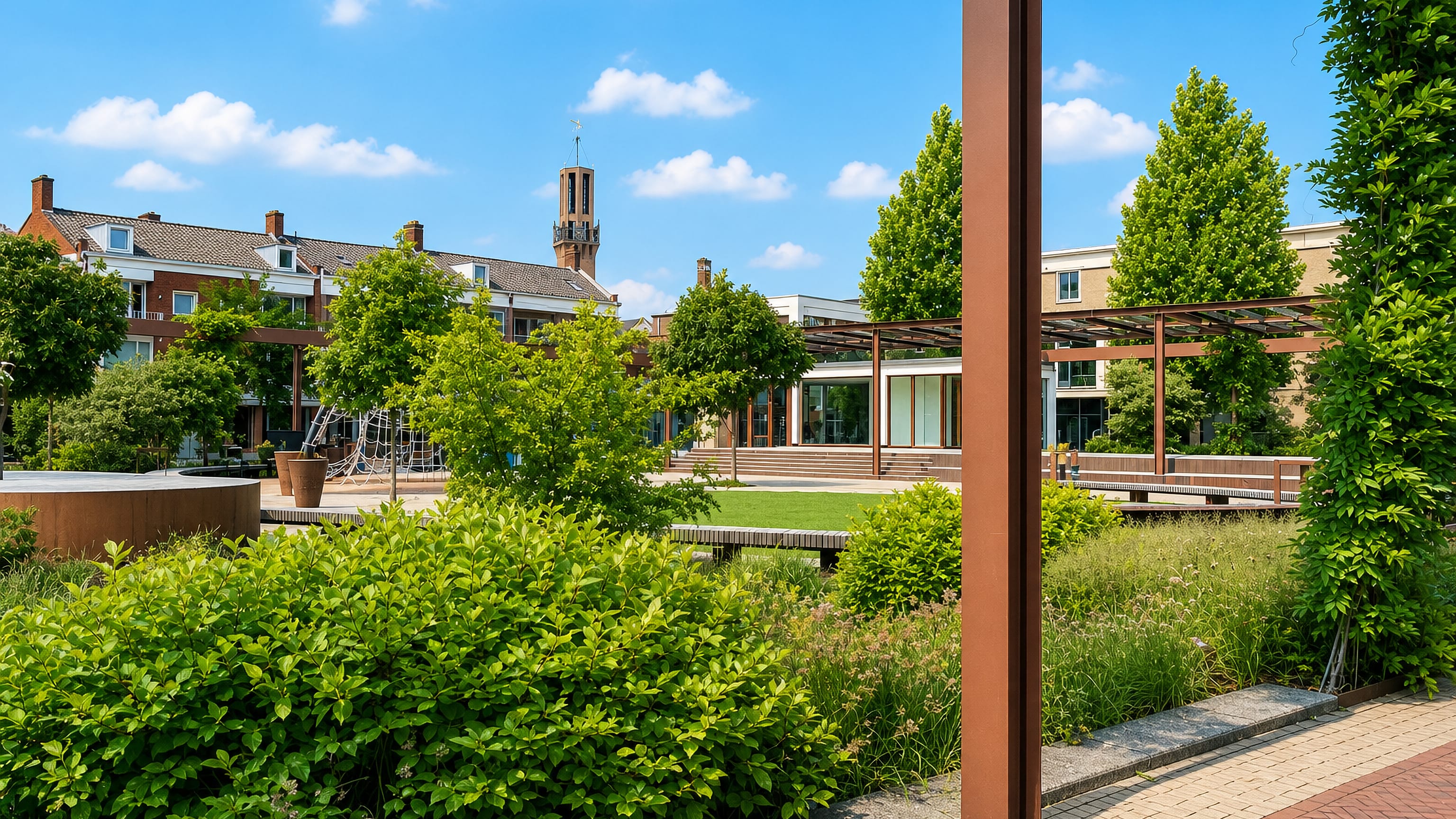 Modern landscaped city-centre square in Hengelo, Netherlands, with a brick church tower rising behind.