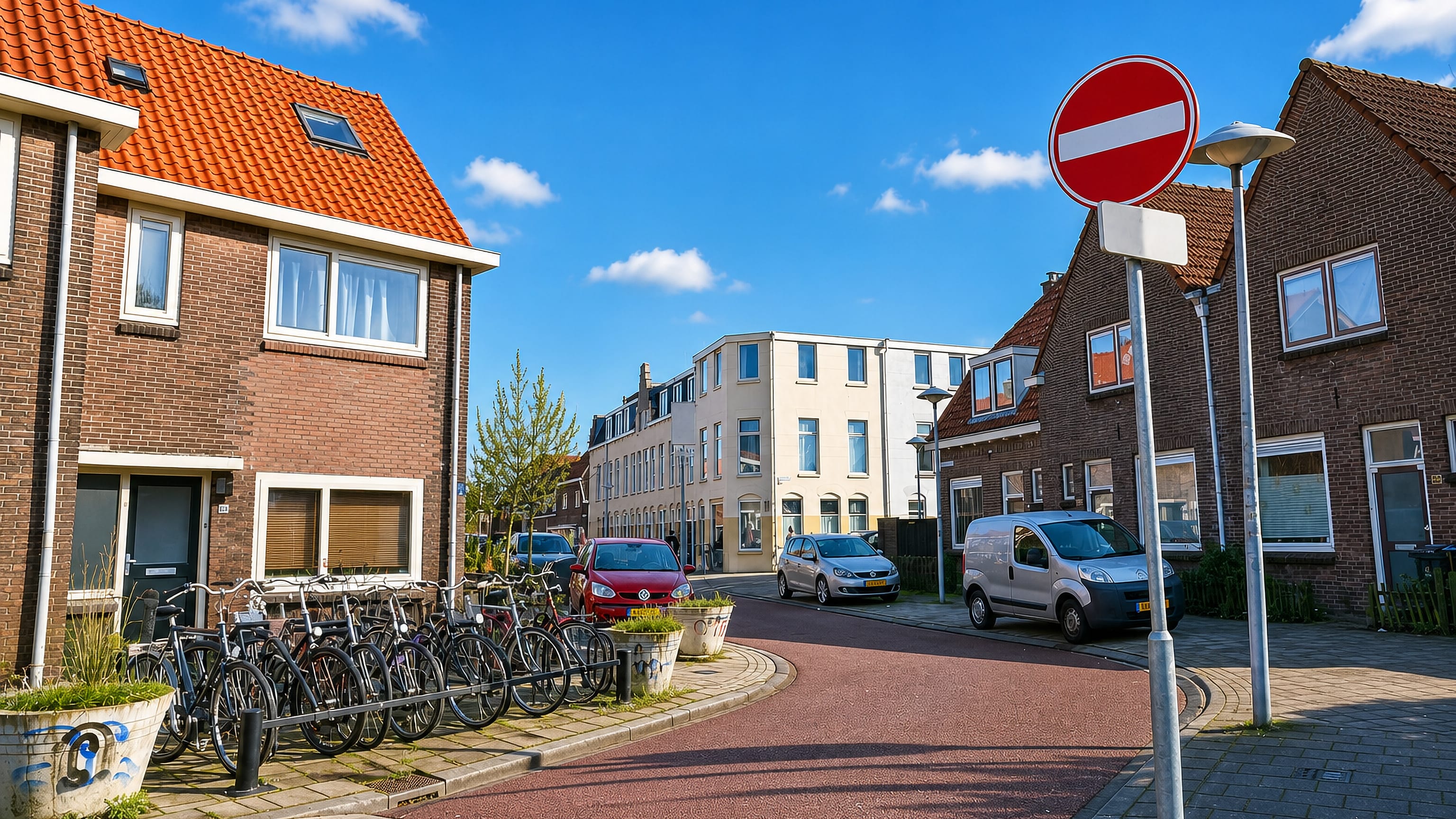 Brick interwar houses and racks of parked bicycles on a red-asphalt street in Zuilen, Utrecht