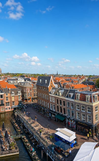 Leiden's Nieuwe Rijn canal lined with historic gabled houses, cafe terraces and boats.