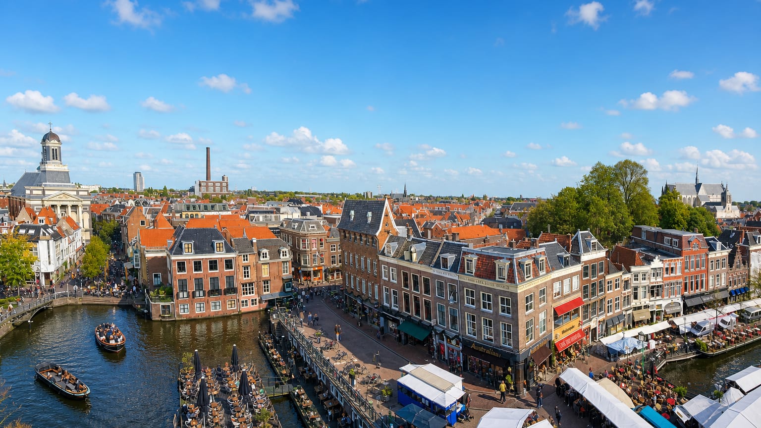 Leiden's Nieuwe Rijn canal lined with historic gabled houses, cafe terraces and boats.