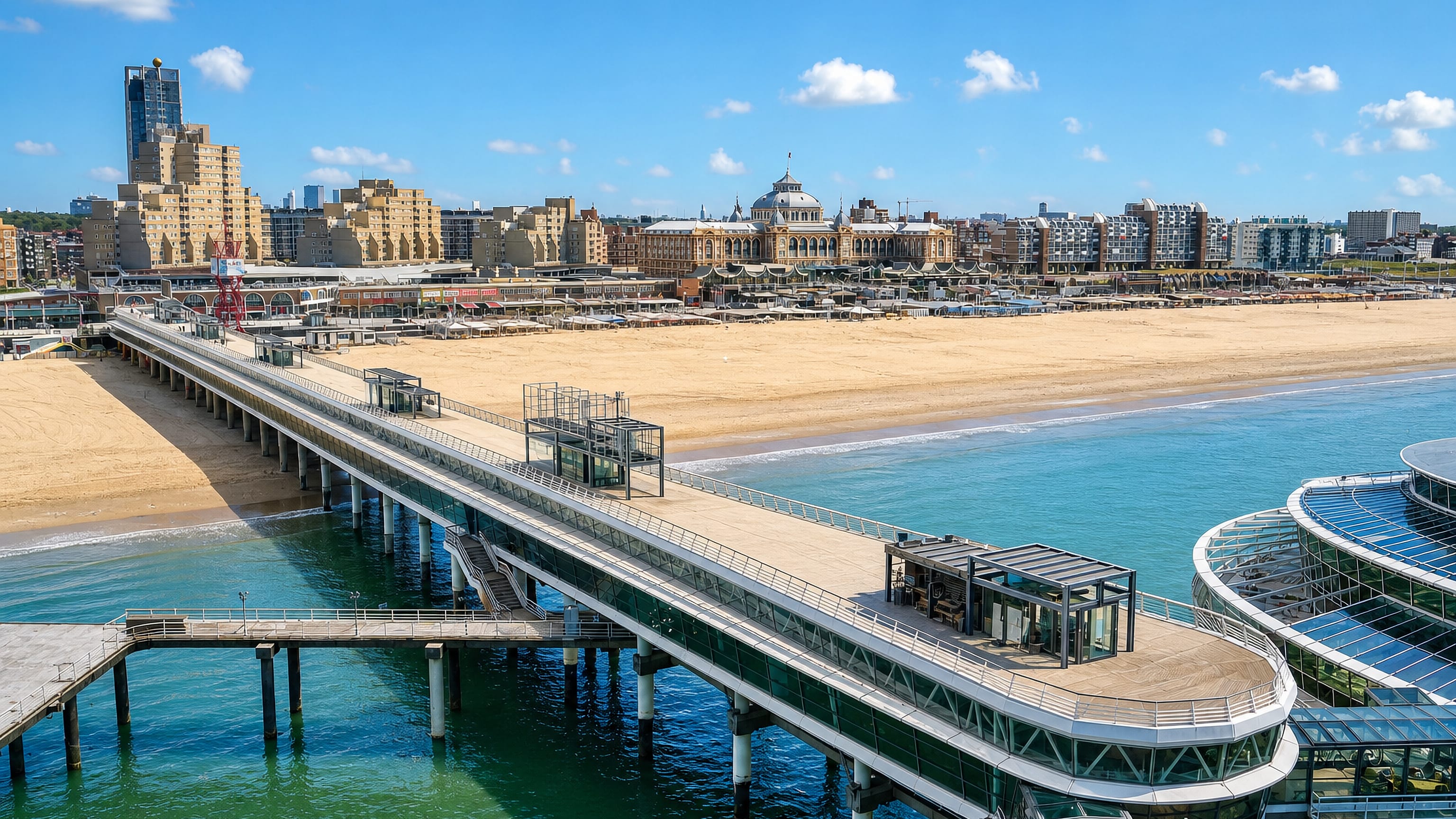 The Pier at Scheveningen reaching over the sea beside the wide beach, with the domed Kurhaus on the boulevard