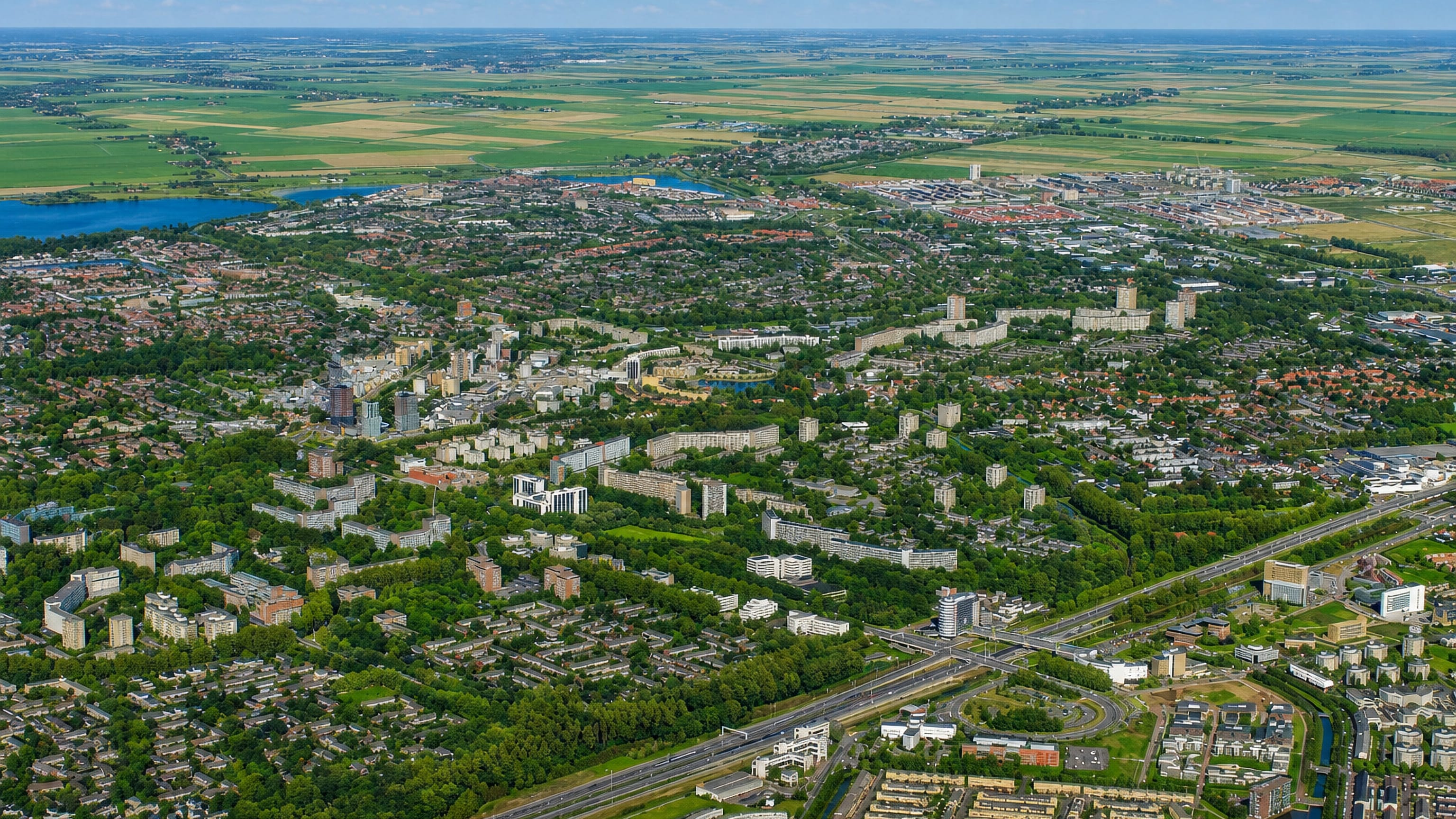 Aerial of Zoetermeer's green suburbs and apartment blocks, with its lake, rail corridor and polder fields beyond.