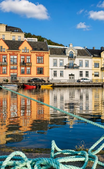 Colourful wooden waterfront houses reflected in Farsund harbour in Agder, southern Norway
