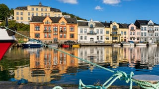 Colourful wooden waterfront houses reflected in Farsund harbour in Agder, southern Norway