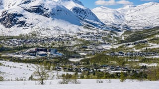 Snow-capped fells rising above the alpine ski village of Hovden, Norway, with scattered cabins and hotels across the valley.