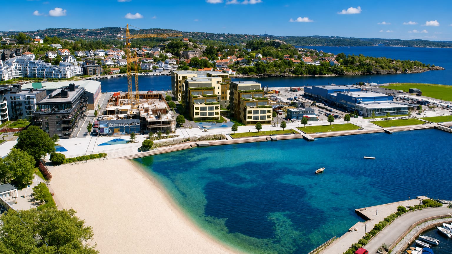 Aerial view of Kristiansand's city beach with turquoise water, a marina and modern waterfront buildings