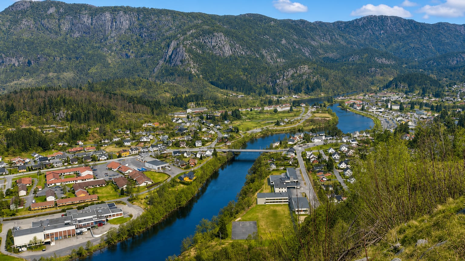 Elevated view of Liknes along the Kvina river with a road bridge and mountains behind