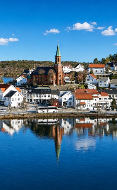 Tvedestrand, Norway, its white wooden houses and green-spired church reflected in the still harbour water