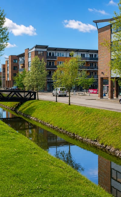 Modern apartment blocks beside a small canal and footbridge in the town centre of Rotnes, Nittedal, Norway.