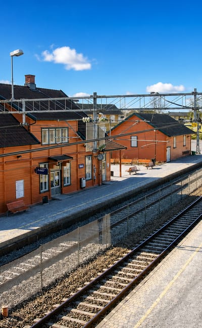 Historic red wooden railway station and platform at Vestby, Norway, under a blue sky