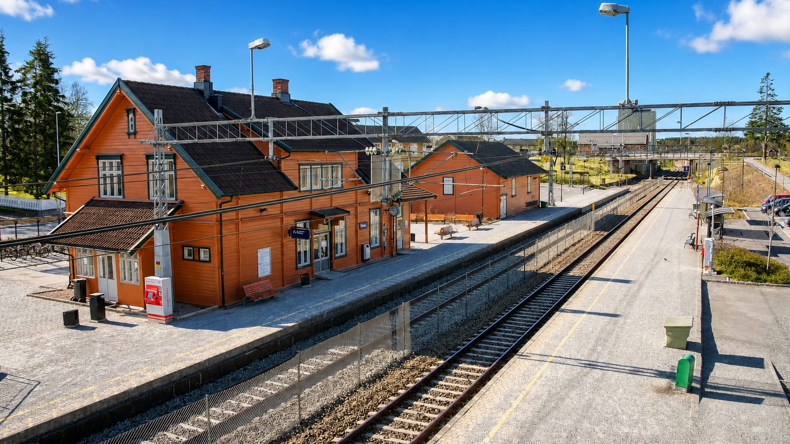 Historic red wooden railway station and platform at Vestby, Norway, under a blue sky
