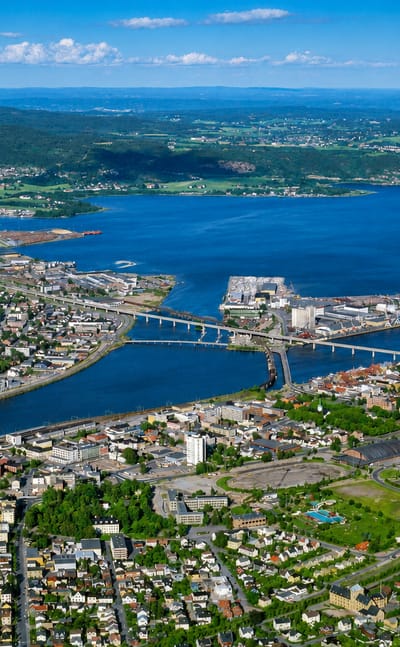 Aerial view of Strømsø, the riverside district of Drammen, Norway, with bridges spanning the Drammen River and forested hills beyond
