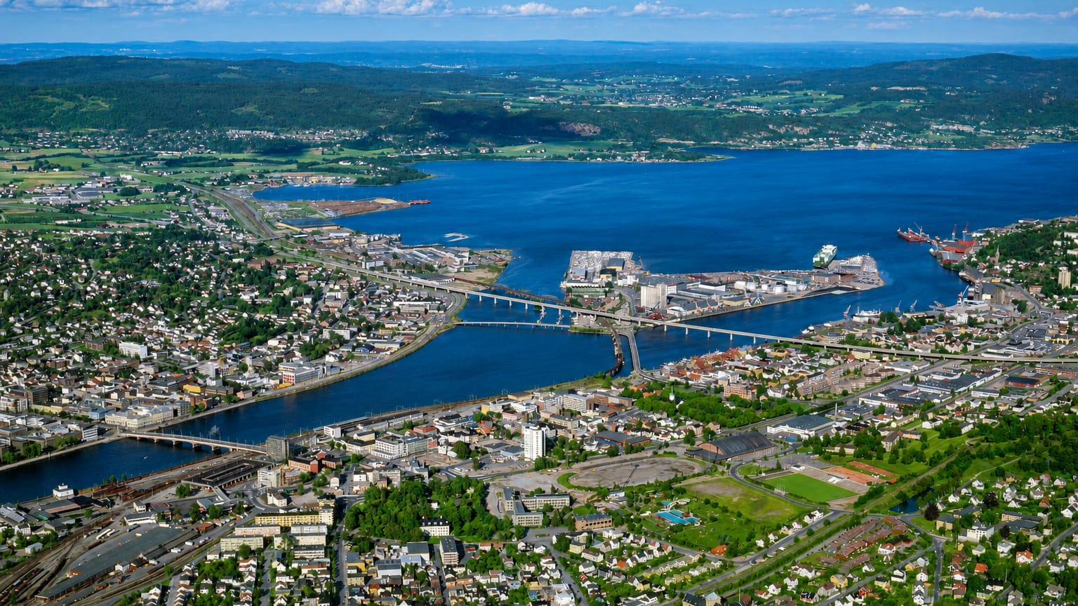 Aerial view of Strømsø, the riverside district of Drammen, Norway, with bridges spanning the Drammen River and forested hills beyond