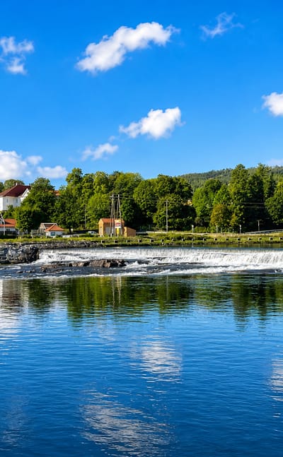 Kongsberg, Norway, its hilltop church rising above a weir on the Numedalslågen river, backed by forested hills