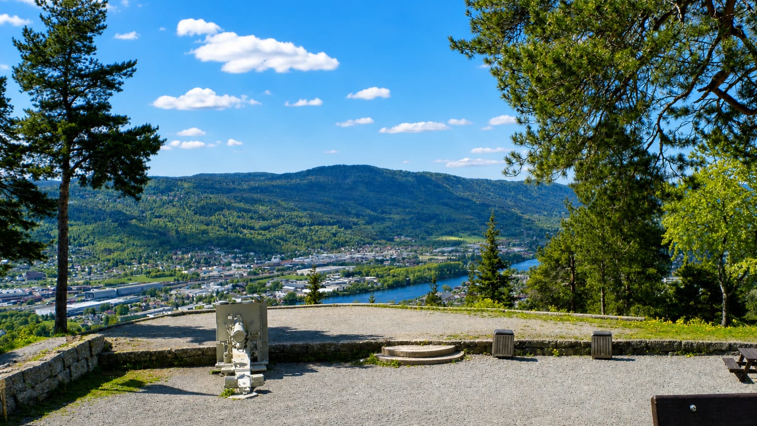 Hillside viewpoint over the Lier valley with a river and Lierbyen spread below forested ridges, Buskerud, Norway.