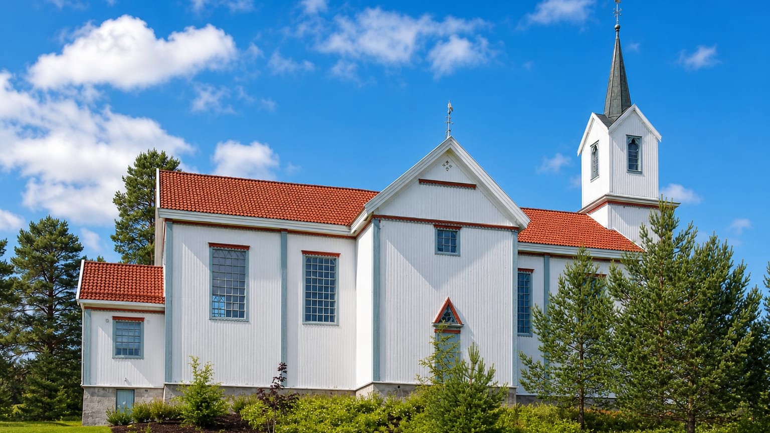 White timber church with a tall steeple and red-tiled roof at Prestfoss in Sigdal, Buskerud, Norway.