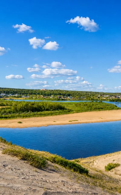 Broad sandy river bend below the tundra plateau with the settlement of Kautokeino, Norway beyond.